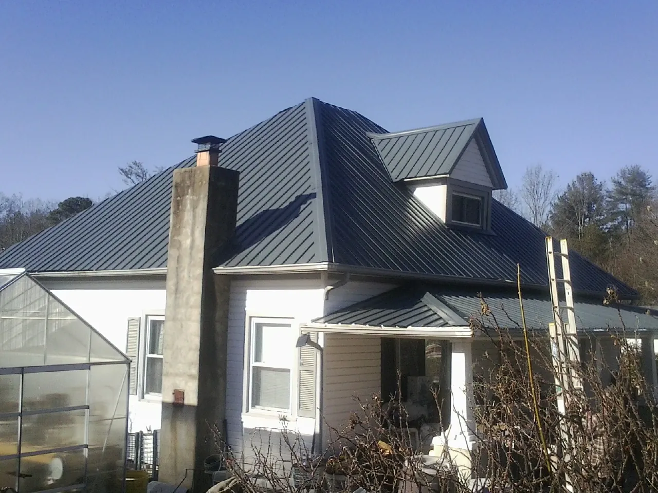 Dark blue standing seam metal roof on a white farmhouse with dormer — Slate & Tile Roof Repair by Roofing Brothers in Boaz