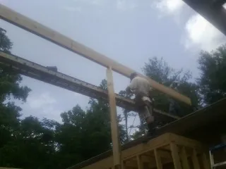 Carpenter setting a ridge beam over a new addition frame — Ice Dam Removal by Roofing Brothers in Boaz