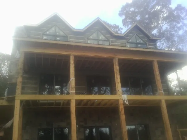 Dormers and porch framing on a large log home under construction — Roof Coating work by our crew in Boaz