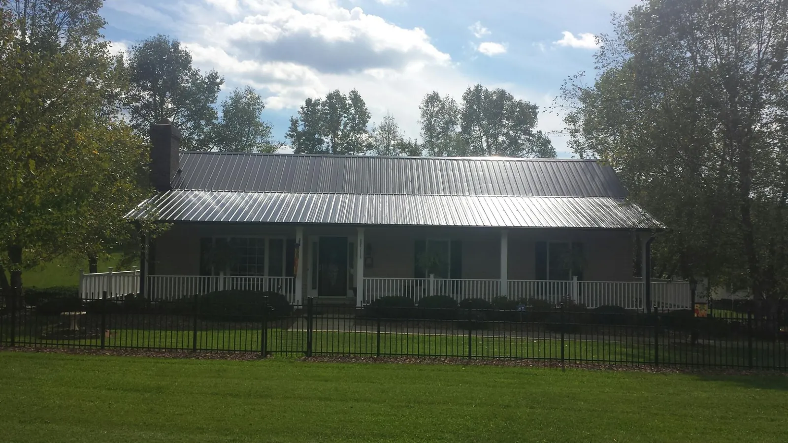 Gray metal roof on a brick ranch with a full width front porch — Gutter Guard Installation work by our crew in Boaz