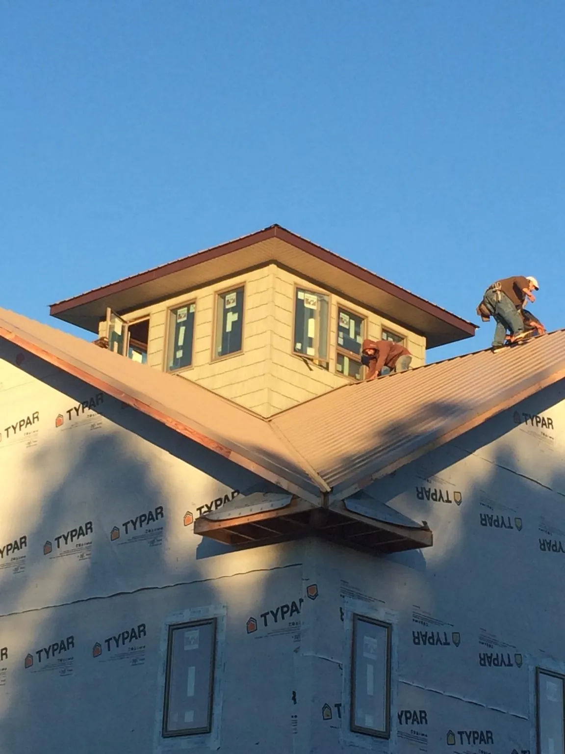 Roofers working around a rooftop cupola on a new metal roof at sunset — Roof Waterproofing in Boaz by Roofing Brothers